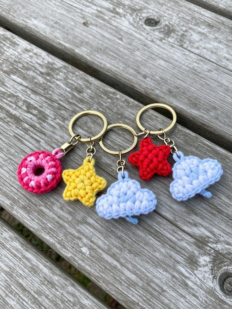 Crocheted keychains featuring a pink donut, yellow star, red star, and blue cloud.