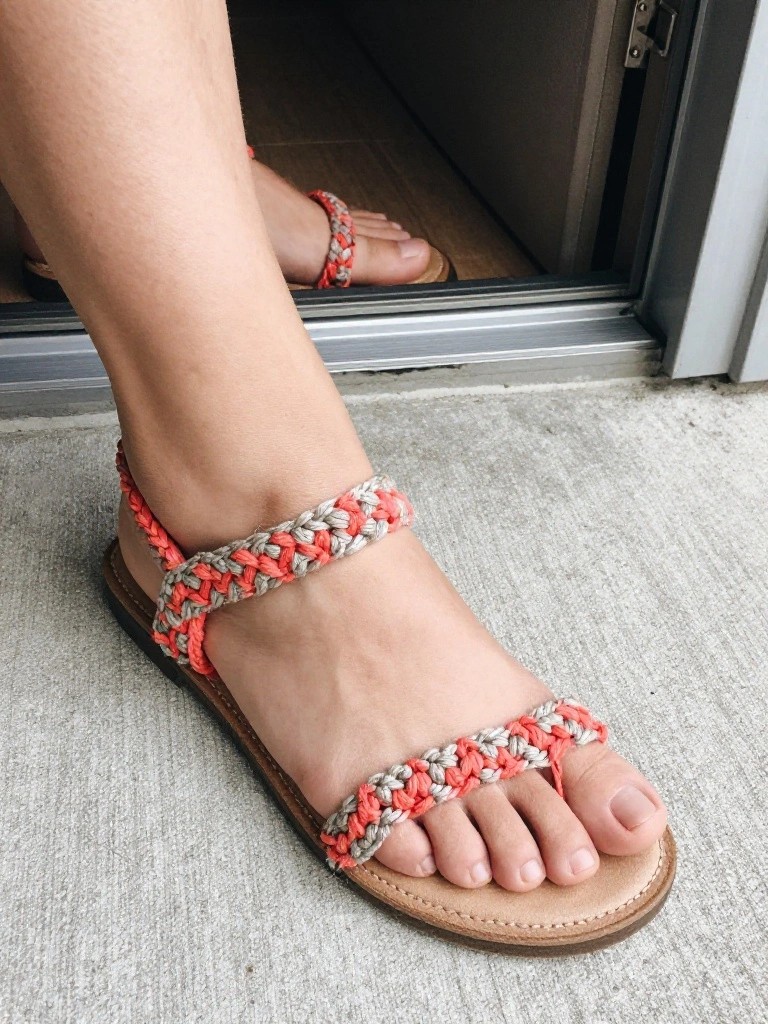 Foot in coral and gray braided ankle-strap sandal with brown sole