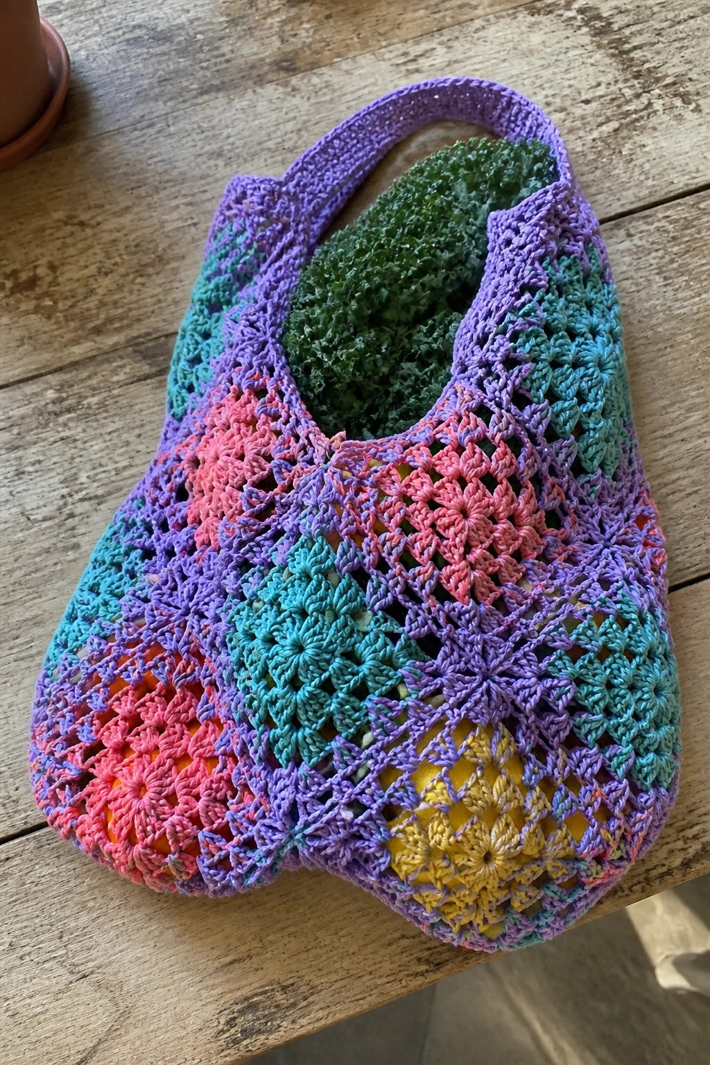 Colorful crocheted granny square tote bag on rustic wooden table