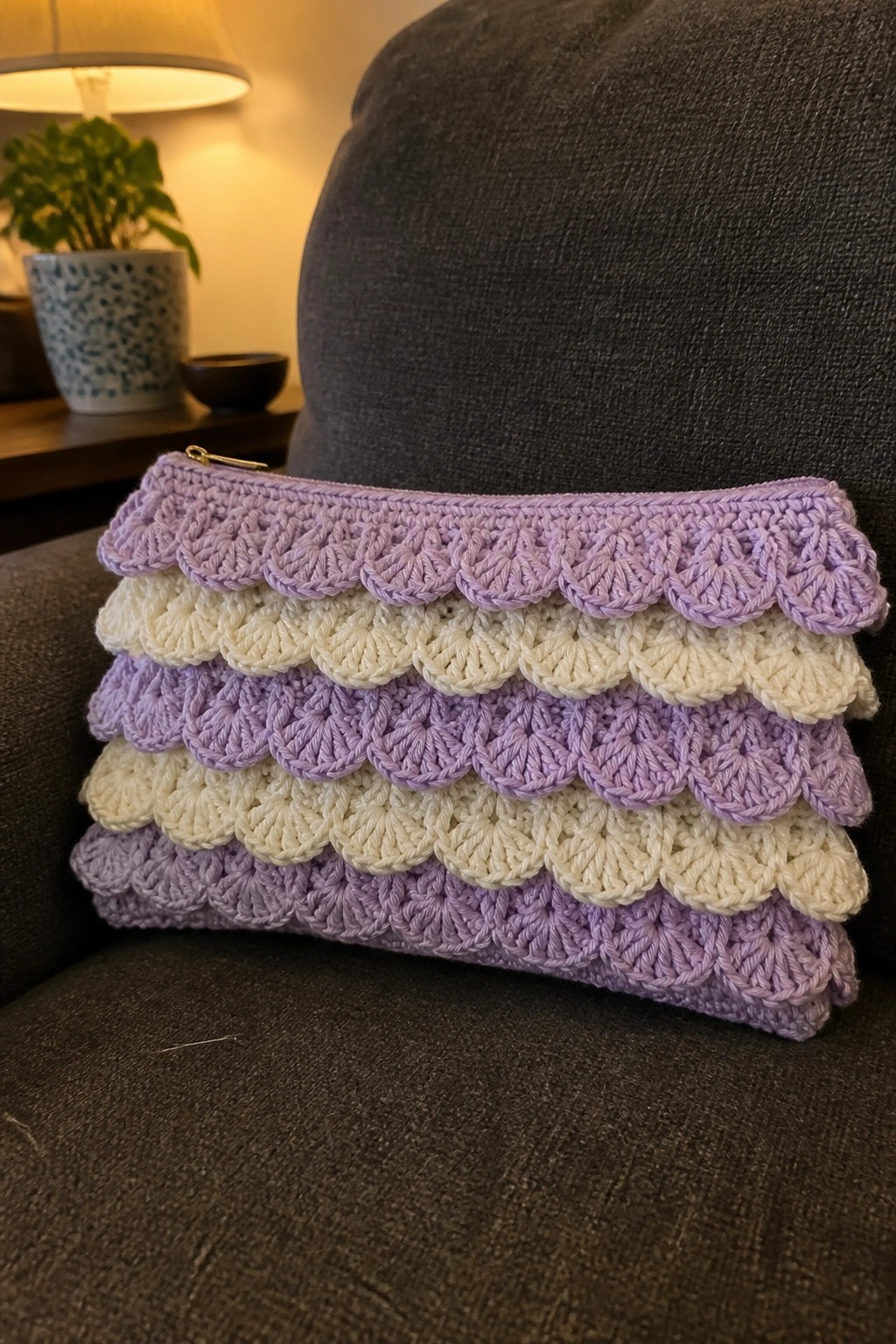 Pastel purple and white crocheted pouch with scalloped layers on gray chair