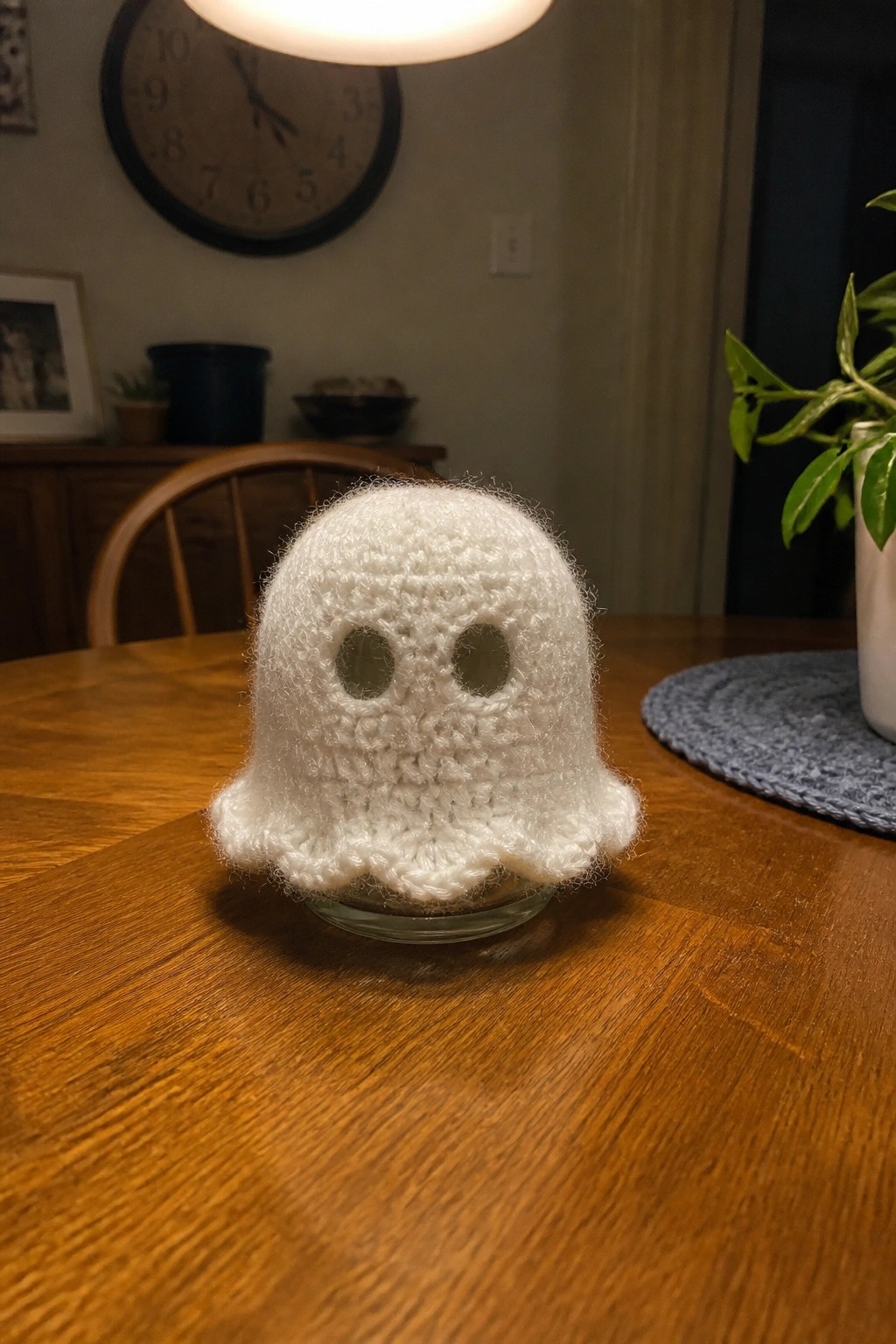 Fluffy white crocheted ghost with eye holes on wooden table surface