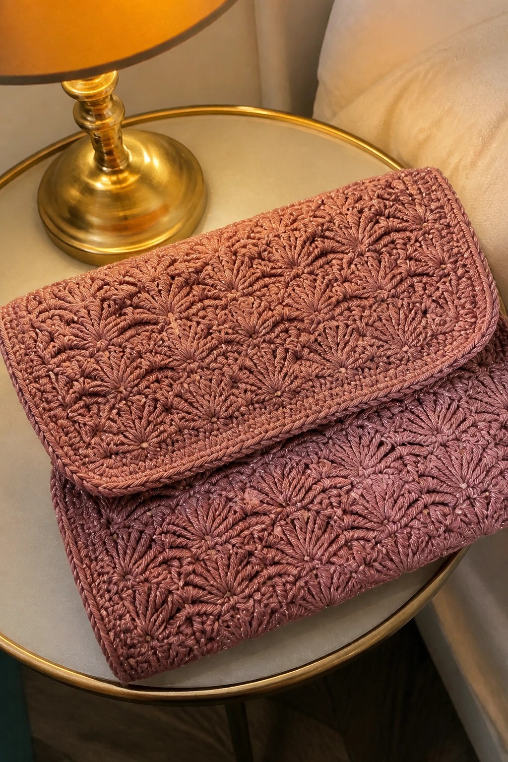 Two dusty rose crocheted clutches with fan patterns on a marble side table.