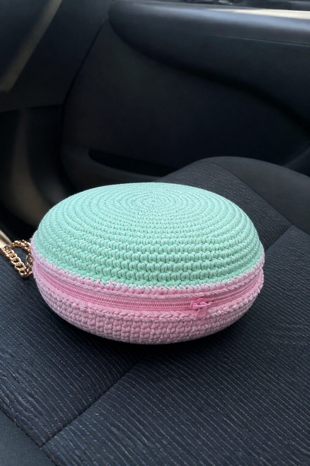 Mint green and pink crocheted round pouch with pink zipper on car seat