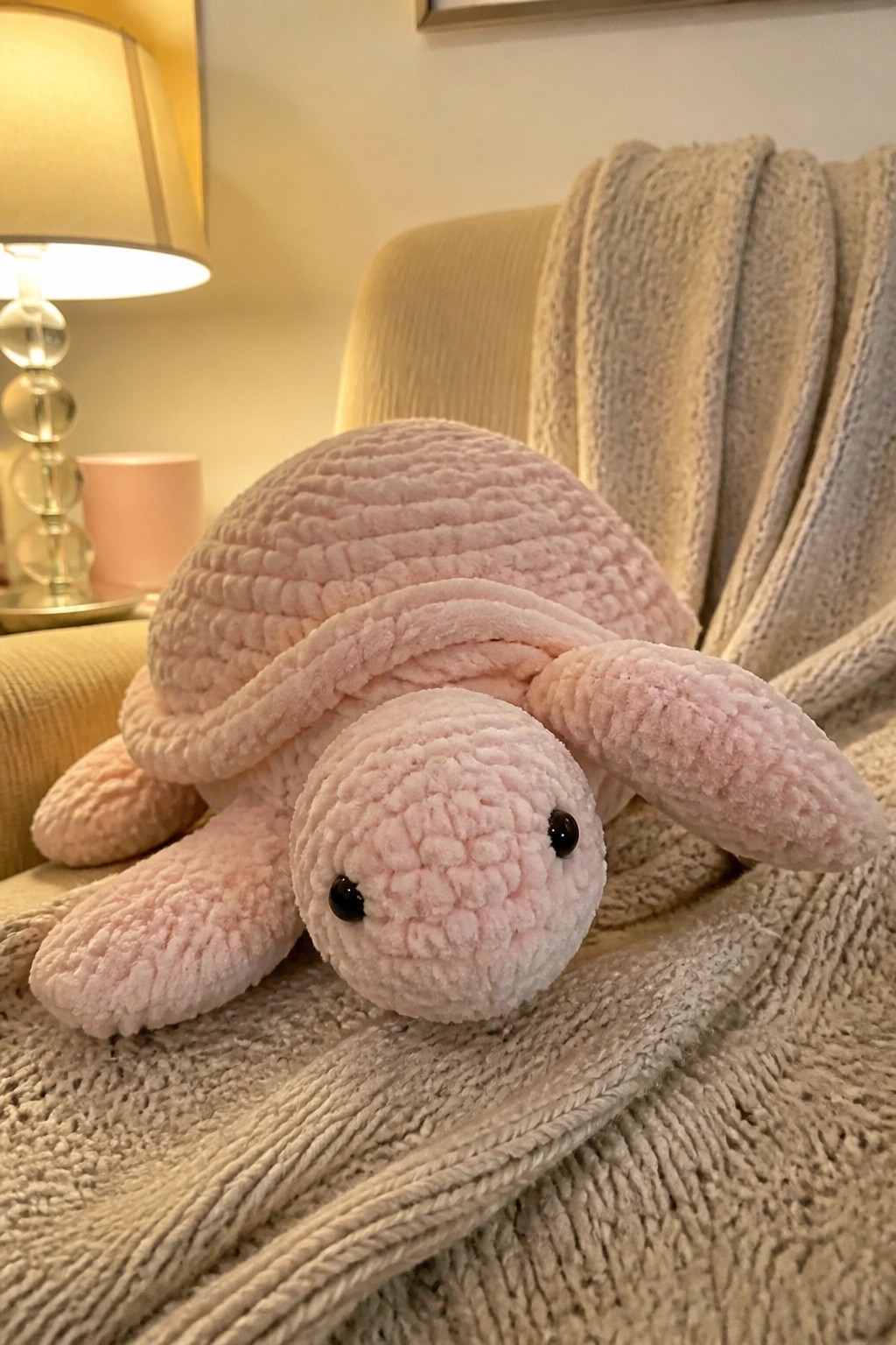 Pink plush turtle toy on beige textured blanket near glowing lamp