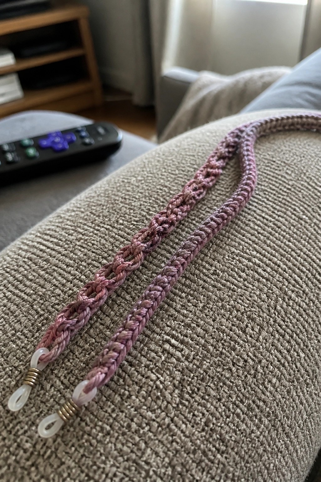 Two pink braided lanyards with looped ends on beige couch fabric