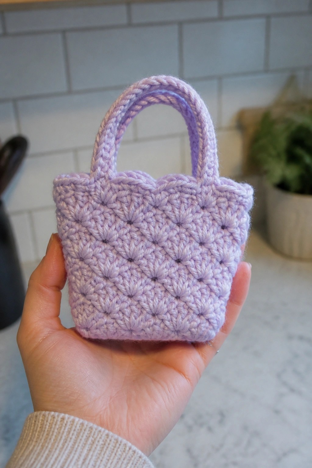 Hand holding tiny lavender crocheted mini tote bag with handle