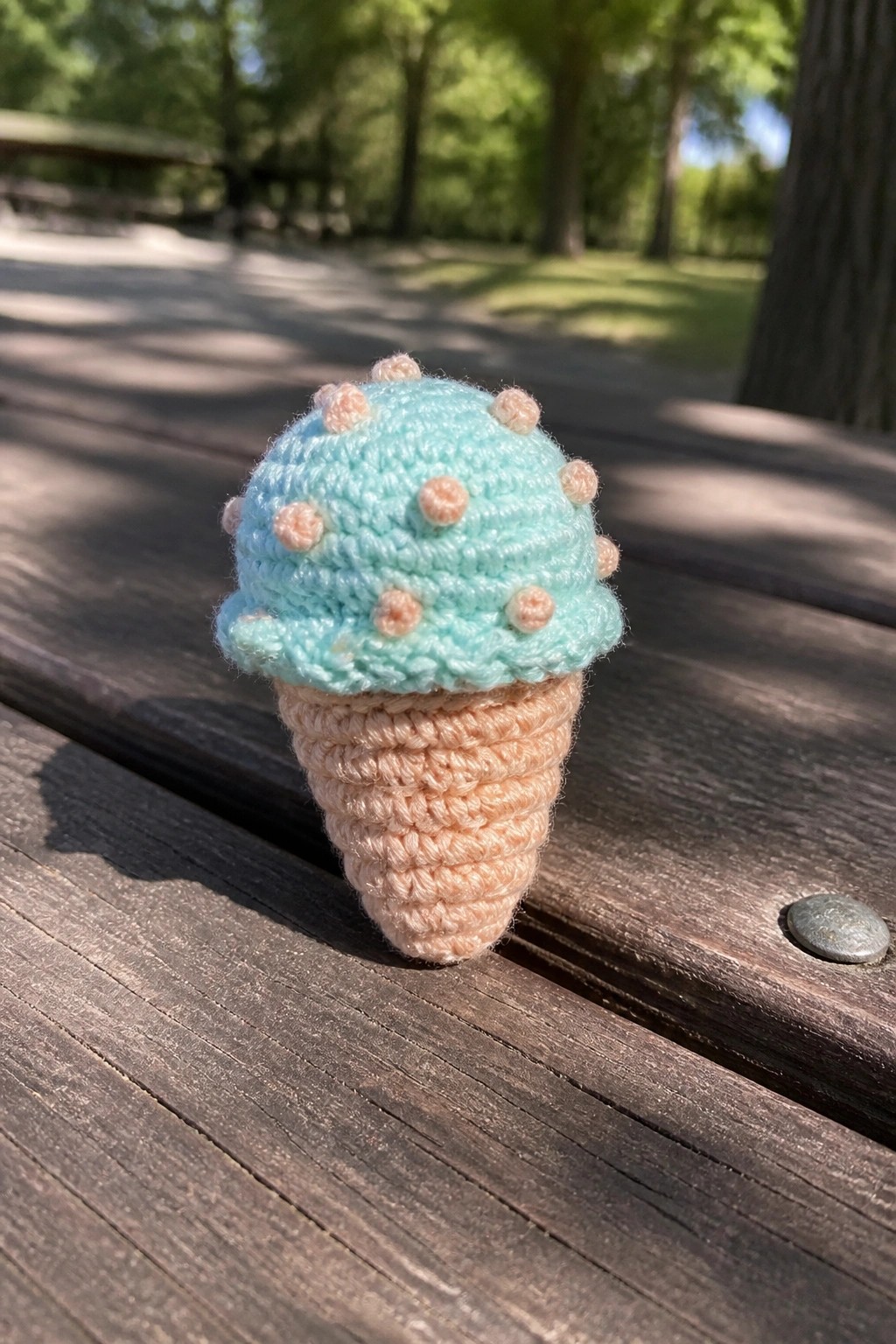 Crocheted mint green ice cream cone with pink dots on wooden table
