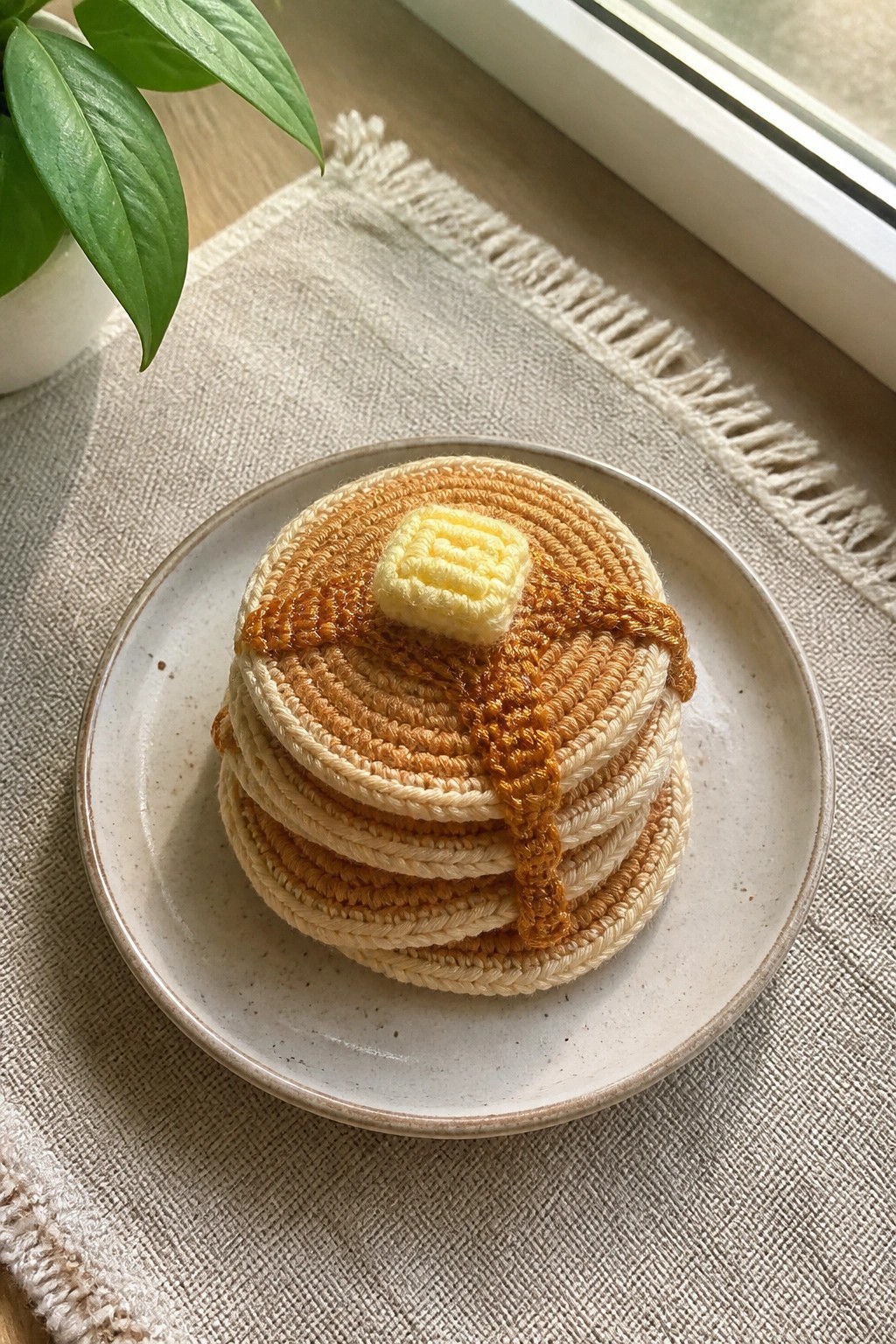 Crocheted pancake stack with yellow butter and syrup on a ceramic plate