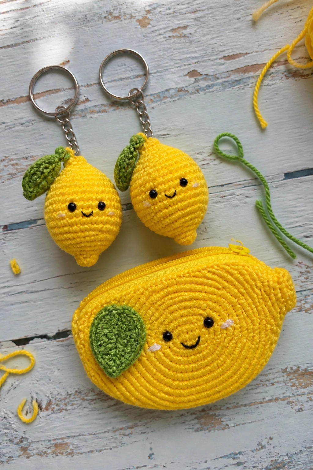 Two crocheted lemon keychains and zippered pouch with faces on wood