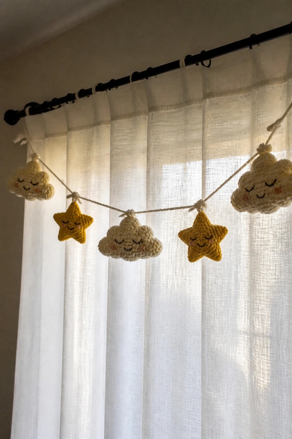 Crocheted yellow stars and cream clouds garland on sheer white curtains