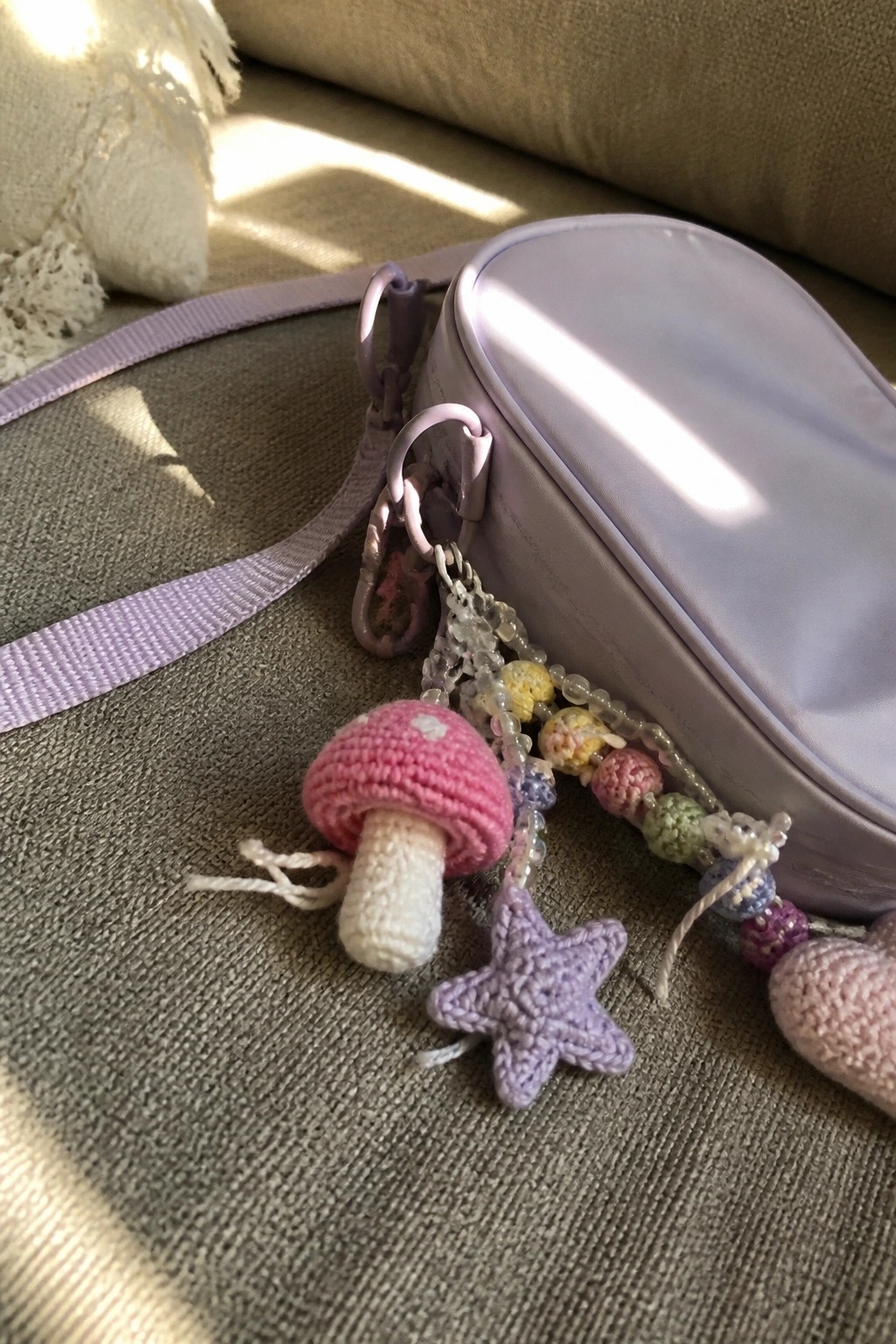 Purple bag with pink crocheted mushroom and purple star keychains on green fabric