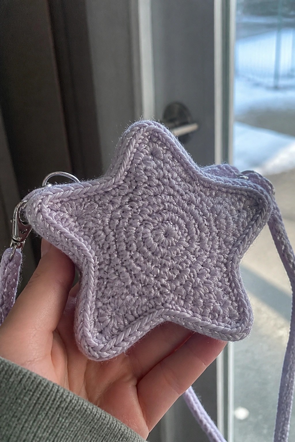 Hand holds sparkly lavender crocheted star bag with metal clasp and strap