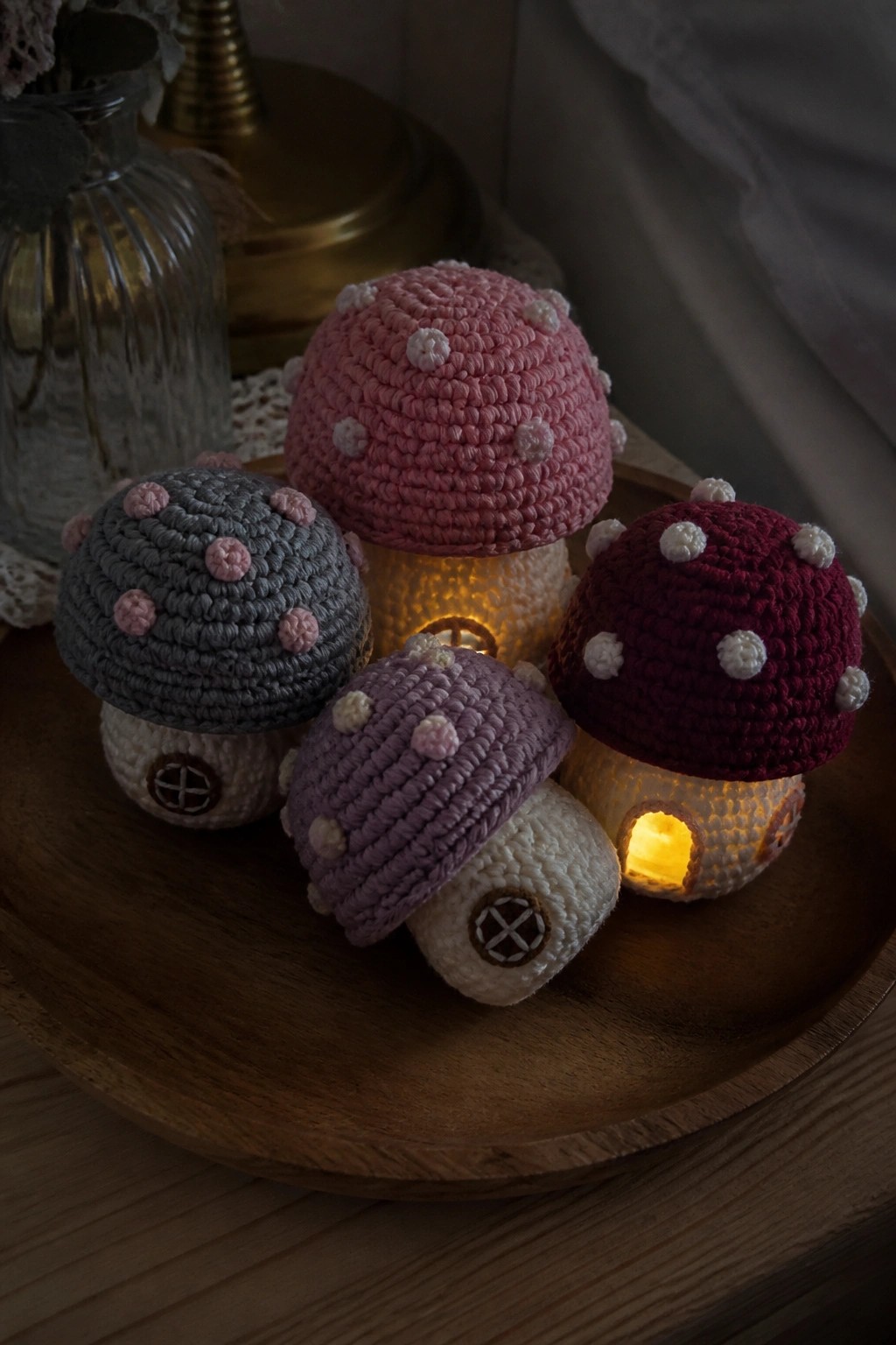 Four colorful crocheted mushroom houses glowing on a wooden tray