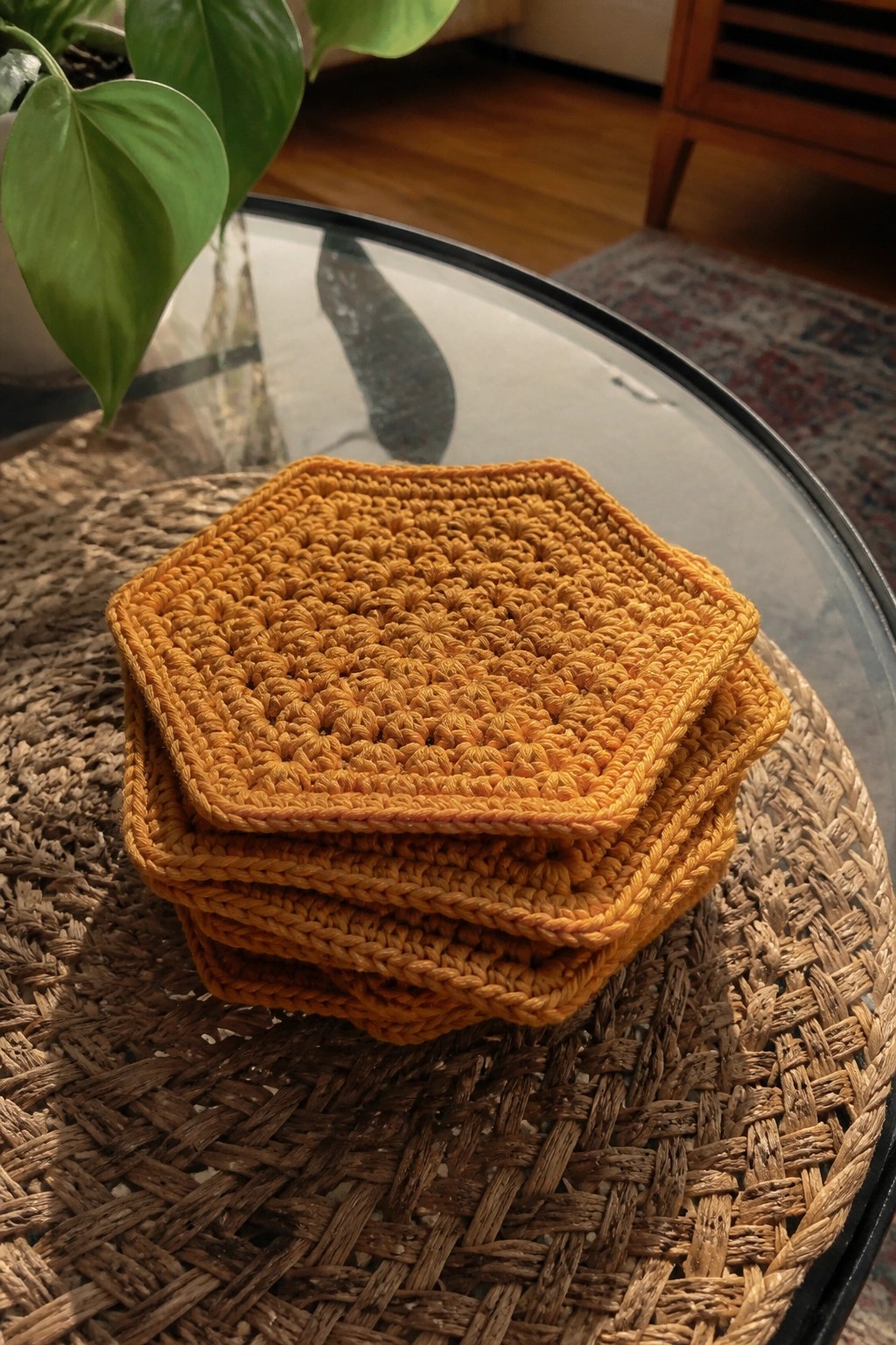 Stack of golden crocheted coasters on woven mat under glass table
