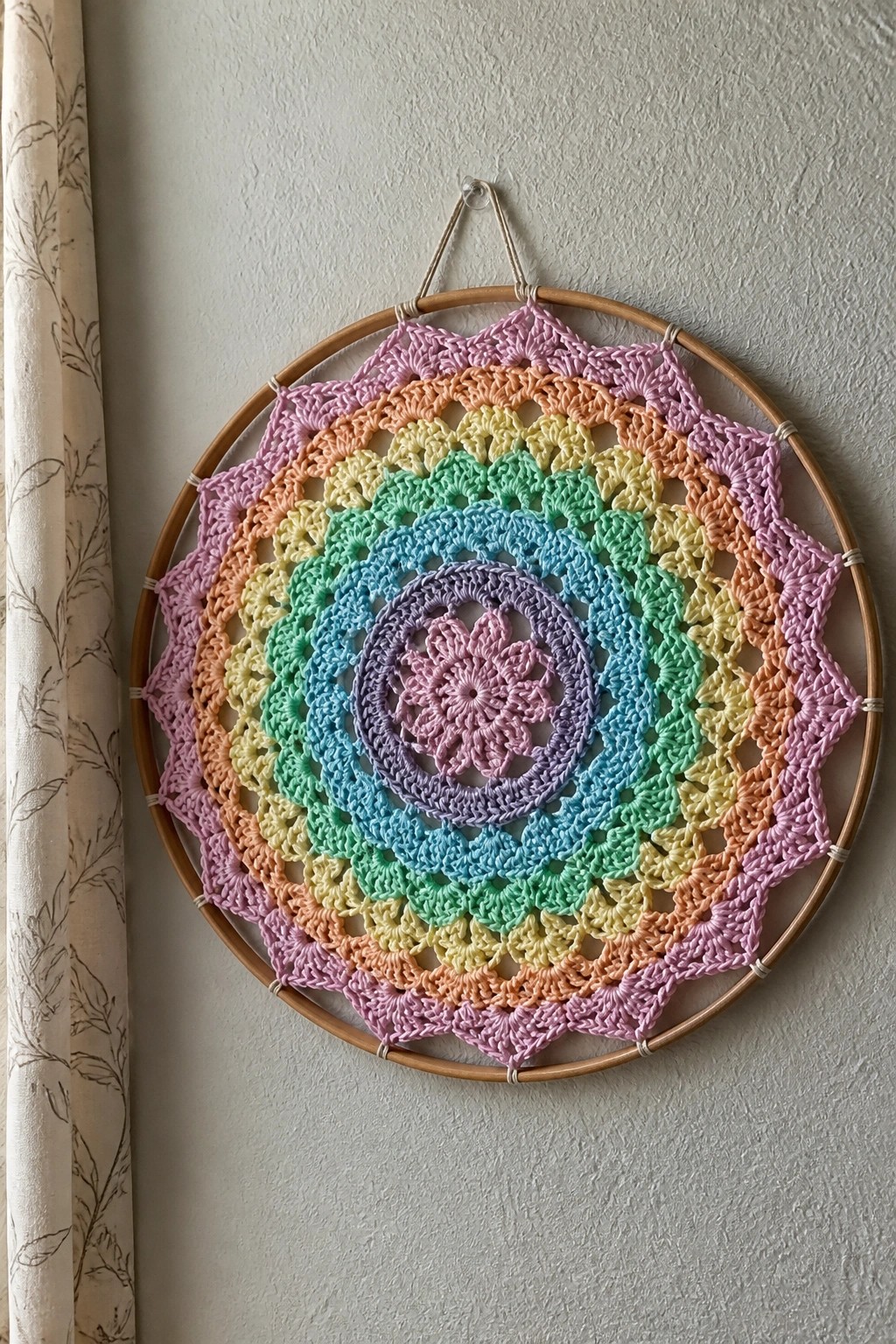 Rainbow crocheted mandala in wooden hoop hanging on wall