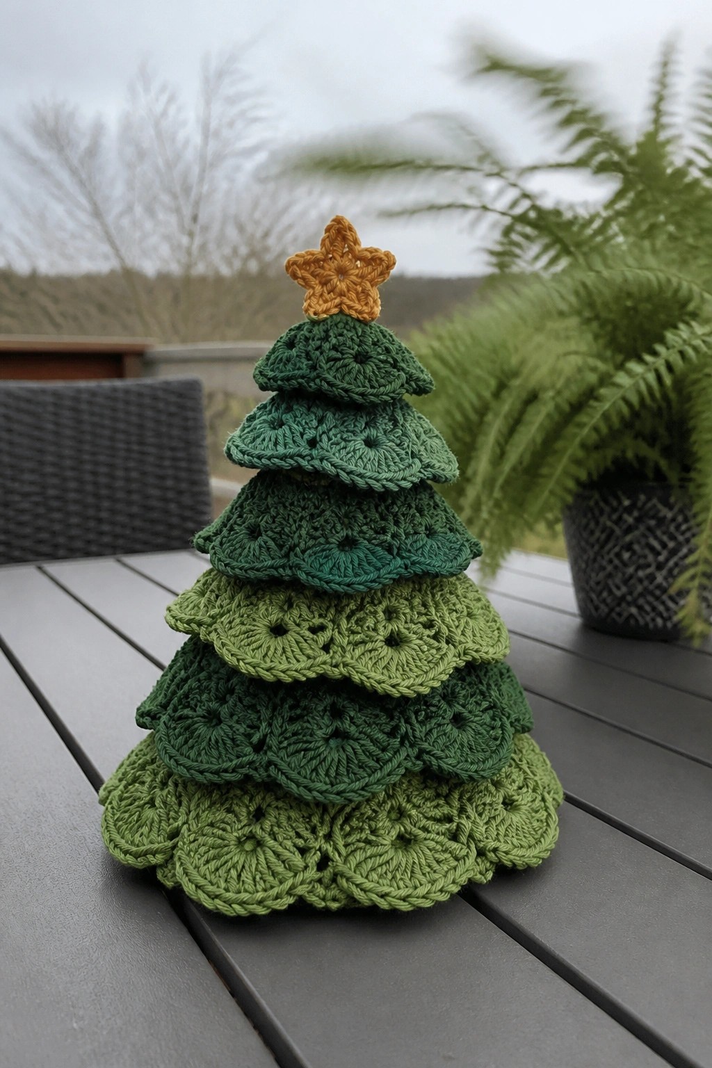 Crocheted Christmas tree of layered greens with yellow star on outdoor table