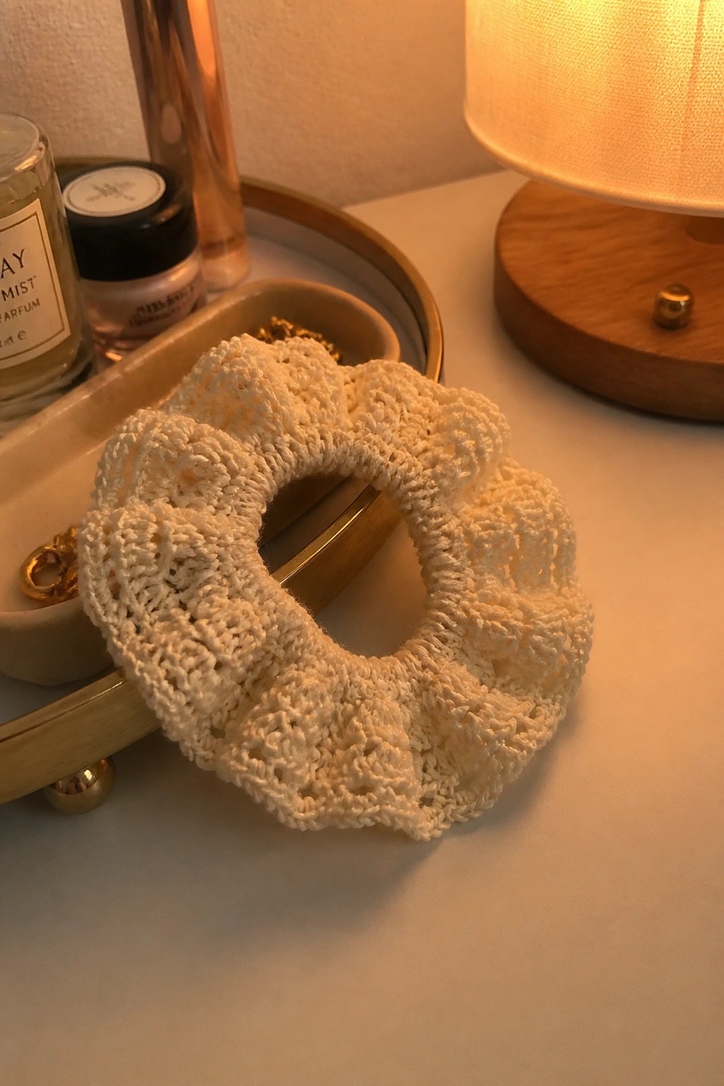 A white crocheted scrunchie with a lacy openwork pattern resting on a vanity surface.