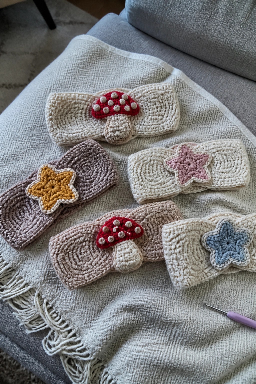 Assorted crocheted headbands with mushroom and star appliques on a fringed blanket.